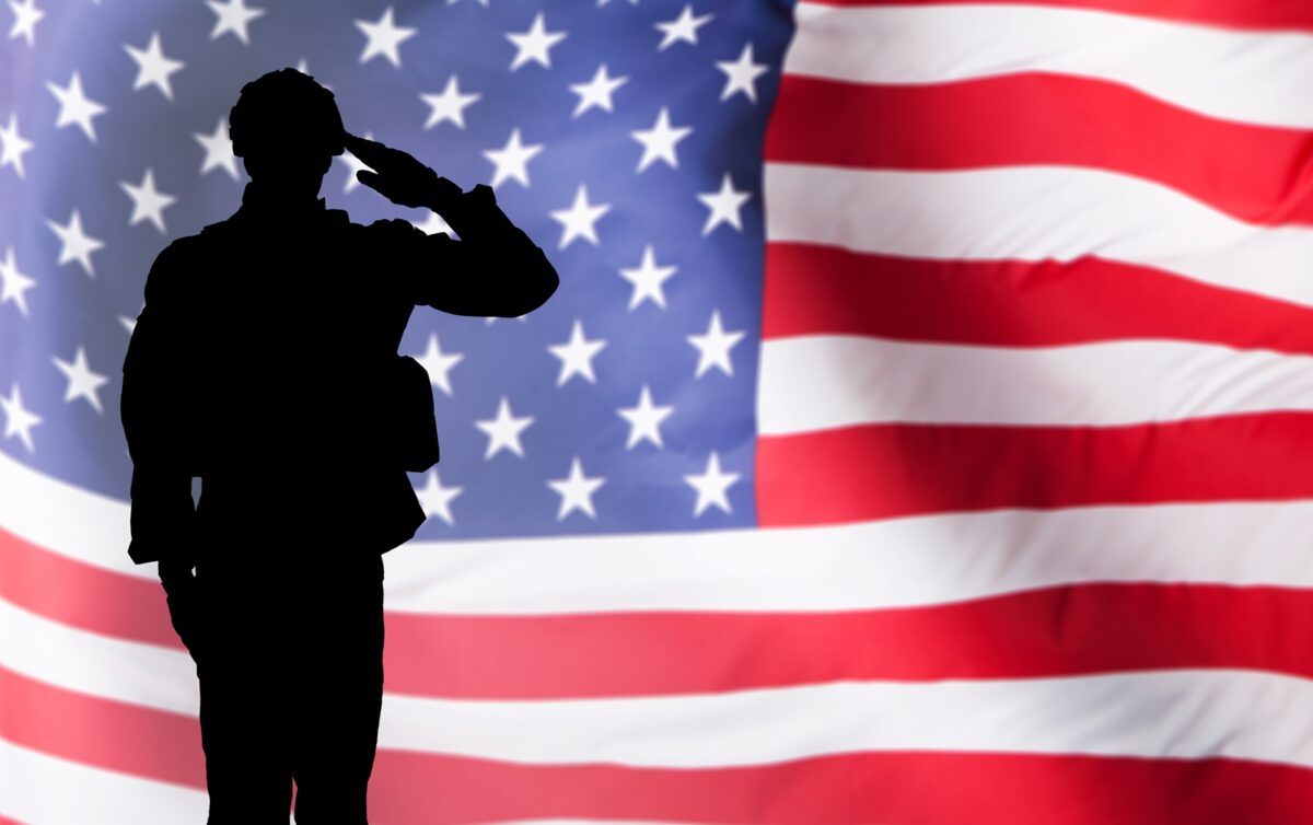 Silhouette,of,a,solider,saluting,against,the,american,flag
